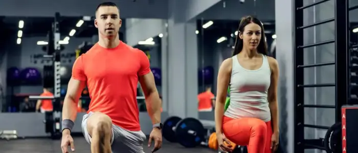 man and woman in gym doing squats, both in custom gym shirts