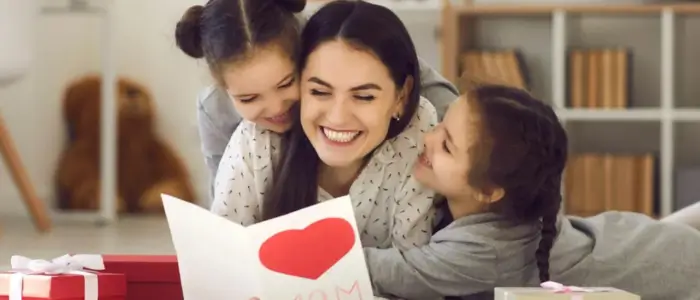 a woman and two children laying on the floor with a card, celebrating mother's day