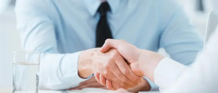 two individuals shaking hands at a meeting, symbolizing good relationships with your suppliers