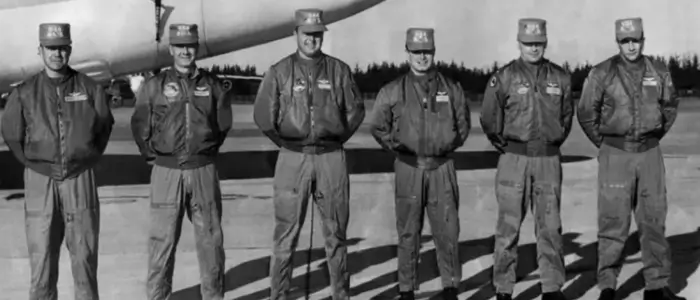 group of men in uniform standing by airplane, showcasing history of bomber jackets