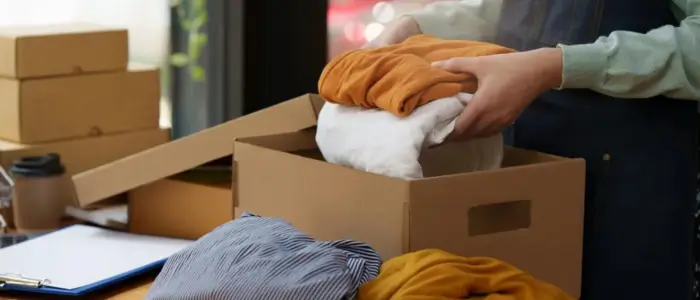 a person packing clothes into a box for recycling