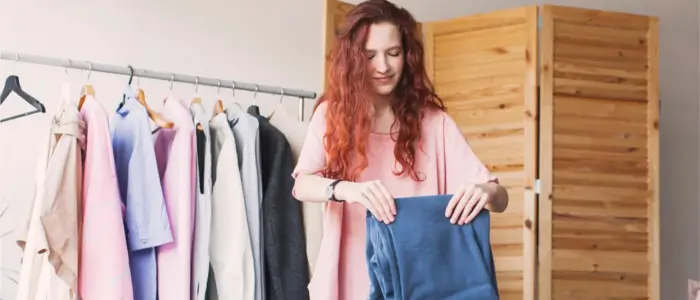 woman holding blue shirt in front of closet, promoting clothes recycling