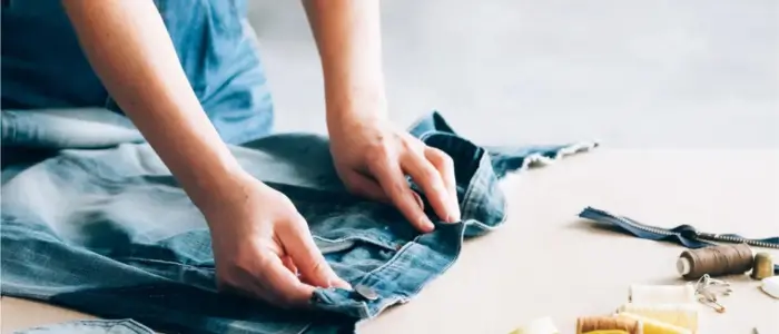 a woman sewing a pair of jeans for recycling clothes on consumer mindsets