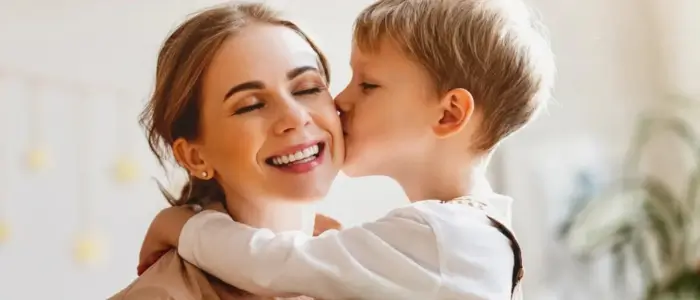 a mother and child embrace in a loving kiss on mother’s day