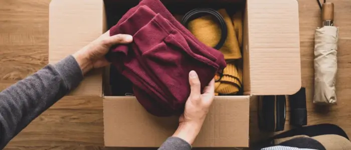 a person packing a box with clothes for recycling