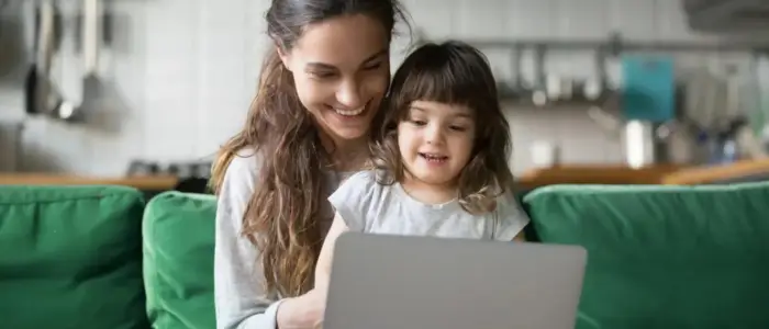 a mother and child sitting on a couch with a laptop, celebrating mother's day