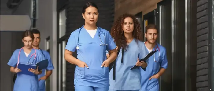 group of nurses in wonderwink scrubs walking down a hallway