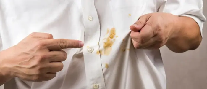man holding a white shirt with a stain on it, showcasing spots and marks with stain removal sorcery