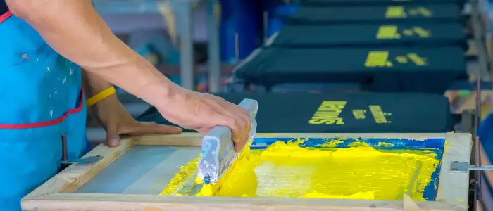 a person applying yellow ink on screen