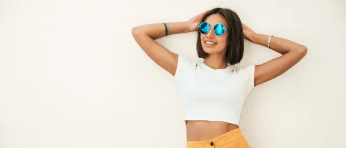 a woman wearing sunglasses and a white crop top