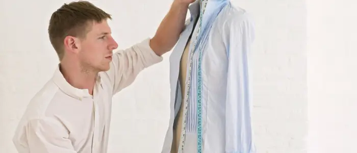  man measuring shirt length against a white wall