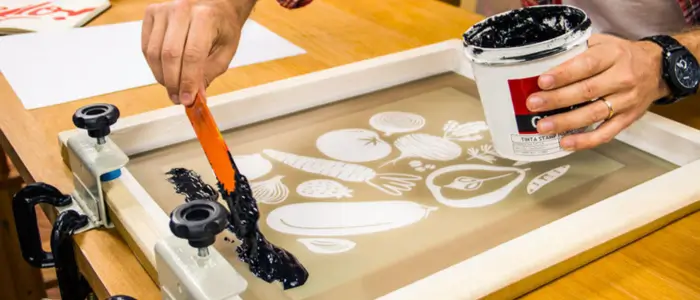 person using a brush to paint on paper, in the process of preparing for screen print