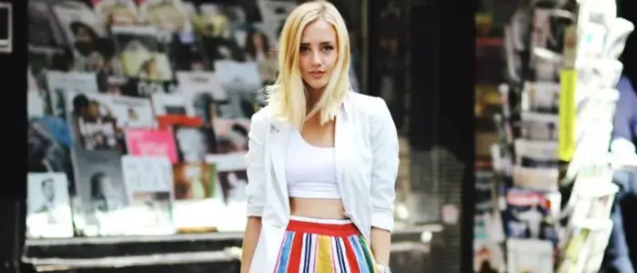 a woman in a winter outfit with a white crop top and colorful skirt