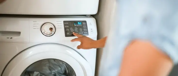 a person stands near a washing machine, noting the shrinkage of nylon fabric during the wash cycle